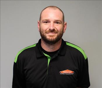 Servpro male employee standing in front of grey wall