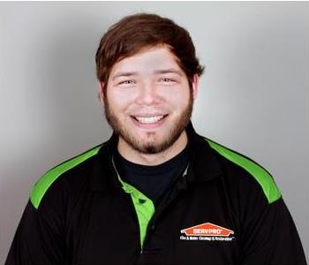 SERVPRO male employee standing in front of grey wall